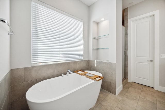 bathroom with tile patterned floors, plus walk in shower, and tile walls