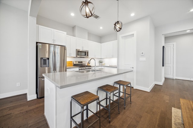 kitchen featuring appliances with stainless steel finishes, dark hardwood / wood-style flooring, sink, a center island with sink, and white cabinetry