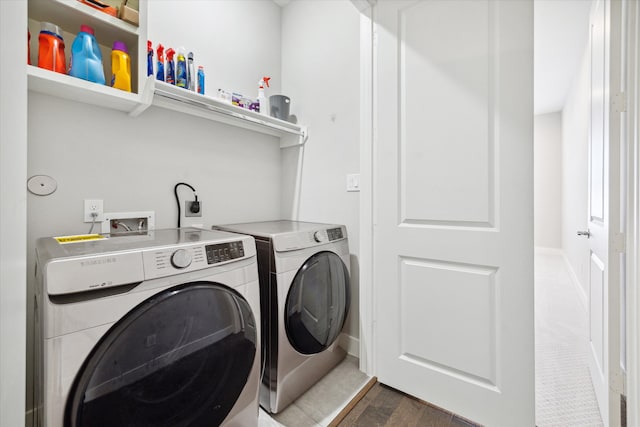 clothes washing area featuring washer and clothes dryer and dark hardwood / wood-style flooring