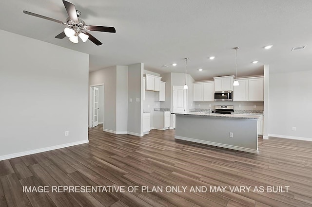 kitchen with hardwood / wood-style floors, a kitchen island with sink, white cabinets, appliances with stainless steel finishes, and light stone counters