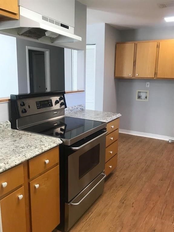 kitchen featuring extractor fan, light hardwood / wood-style flooring, and stainless steel range with electric cooktop