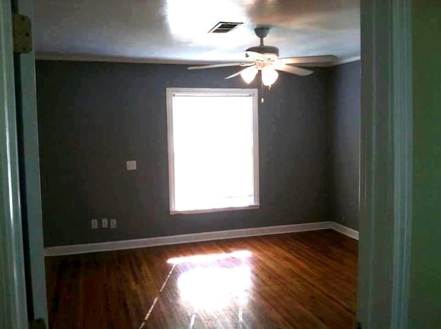 unfurnished room with crown molding, dark wood-type flooring, and ceiling fan