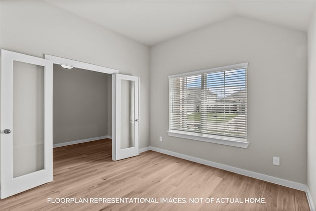 unfurnished bedroom featuring light wood-type flooring, a closet, french doors, and vaulted ceiling