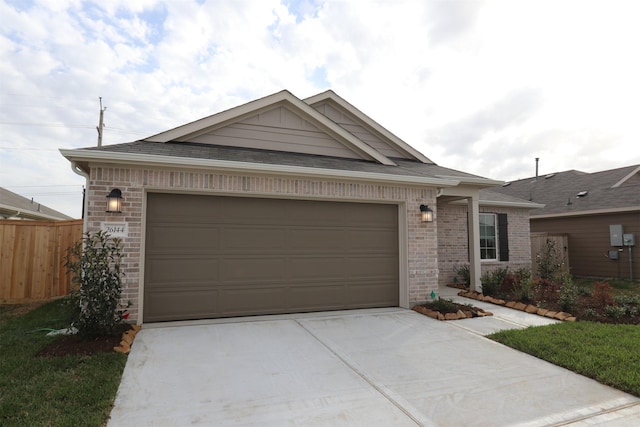 view of front facade with a garage, brick siding, driveway, and fence