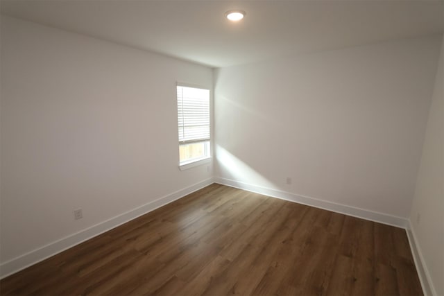 spare room featuring dark wood-style floors and baseboards