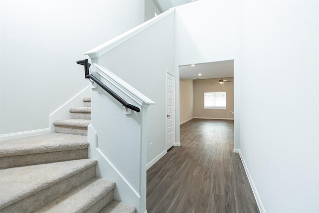 stairway with hardwood / wood-style floors, ceiling fan, and a high ceiling