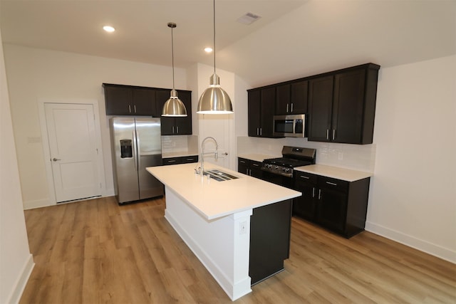 kitchen with a kitchen island with sink, stainless steel appliances, visible vents, light countertops, and pendant lighting