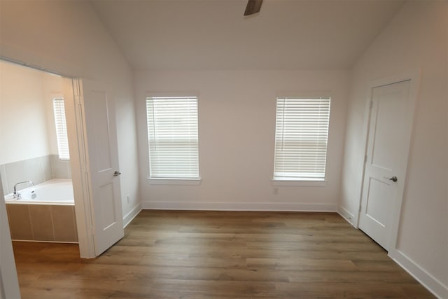 unfurnished bedroom featuring vaulted ceiling, multiple windows, and dark wood-style floors