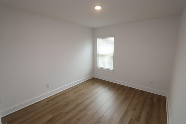 empty room featuring dark wood-style flooring and baseboards