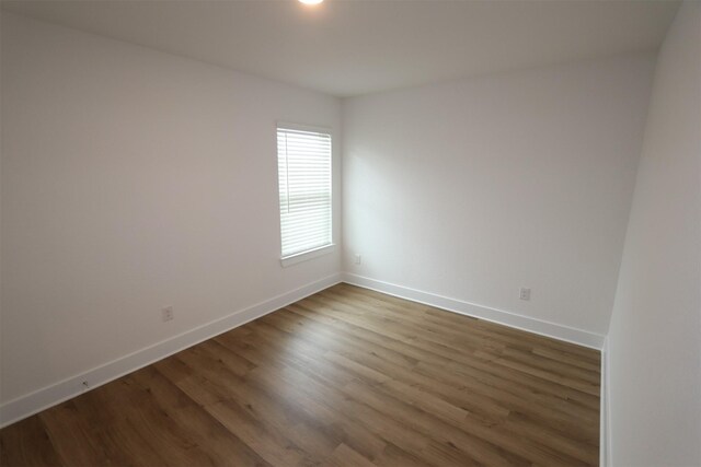 empty room with dark wood-style floors and baseboards