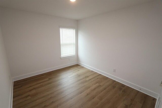 spare room with baseboards and wood finished floors