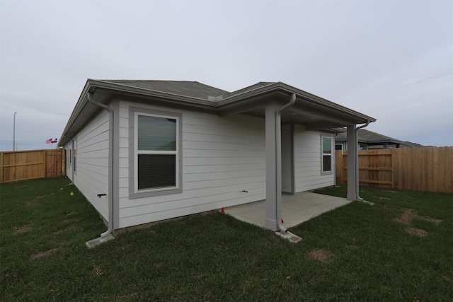 rear view of house featuring a patio, a lawn, and a fenced backyard