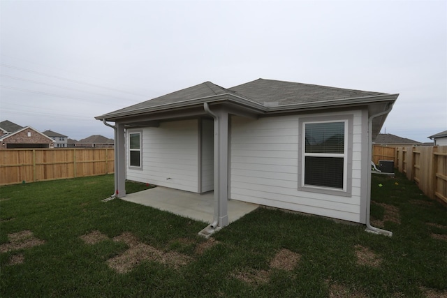 rear view of house featuring a yard, a shingled roof, a patio area, and a fenced backyard