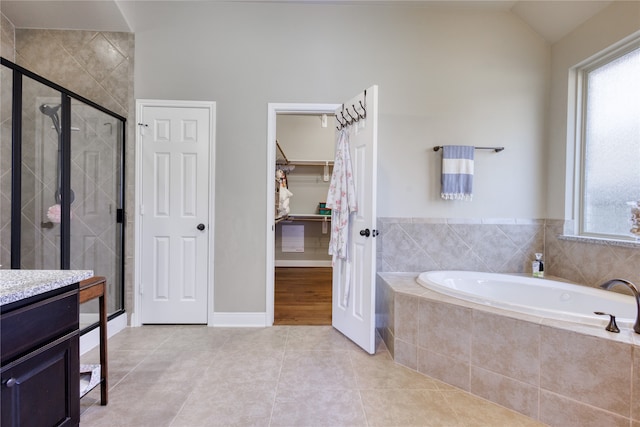 bathroom featuring vanity, lofted ceiling, a healthy amount of sunlight, and plus walk in shower