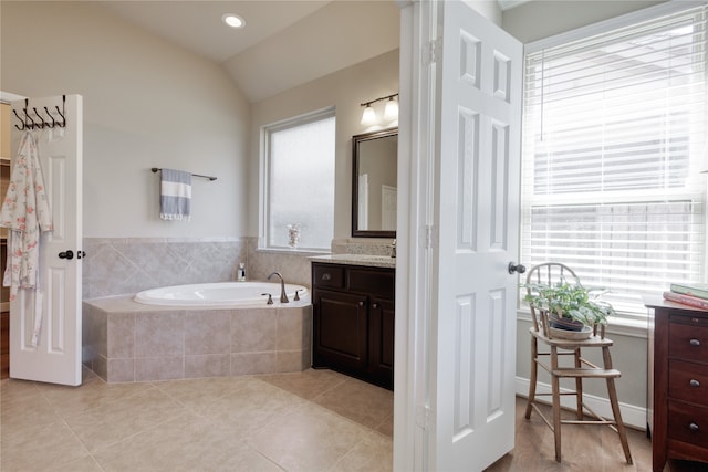 bathroom featuring vanity, a relaxing tiled tub, tile patterned flooring, and vaulted ceiling