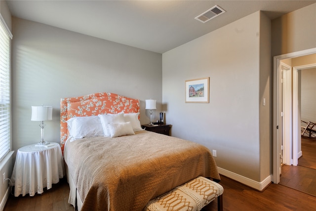 bedroom featuring multiple windows and dark hardwood / wood-style flooring