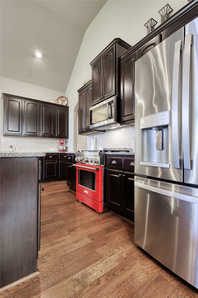 kitchen featuring dark wood-type flooring, dark brown cabinets, appliances with stainless steel finishes, and lofted ceiling