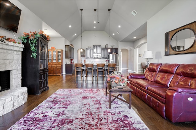 living room with a fireplace, dark hardwood / wood-style floors, and high vaulted ceiling