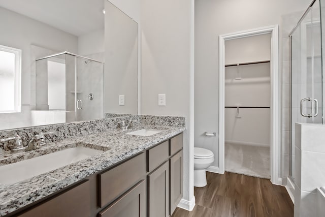 bathroom with a shower with door, vanity, hardwood / wood-style flooring, and toilet