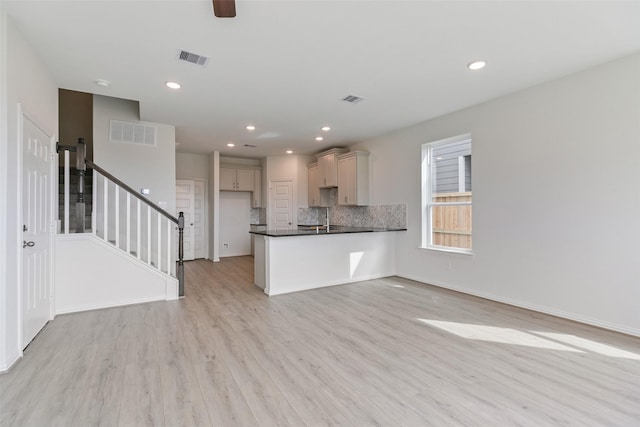 kitchen with light wood-style floors, visible vents, dark countertops, and decorative backsplash