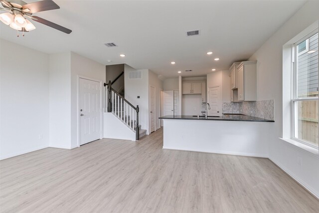 kitchen featuring visible vents, a sink, dark countertops, light wood-type flooring, and backsplash