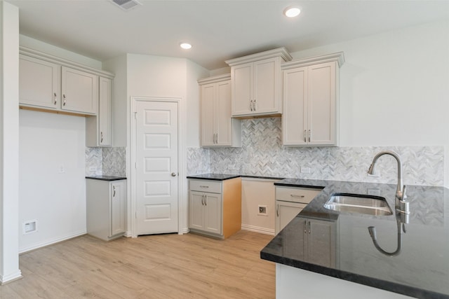 kitchen with visible vents, a sink, tasteful backsplash, recessed lighting, and light wood finished floors