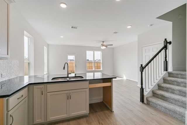 kitchen with visible vents, open floor plan, a peninsula, light wood-style floors, and a sink