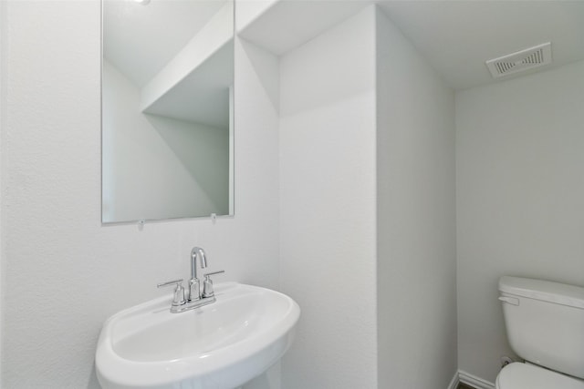 bathroom featuring visible vents, toilet, and a sink