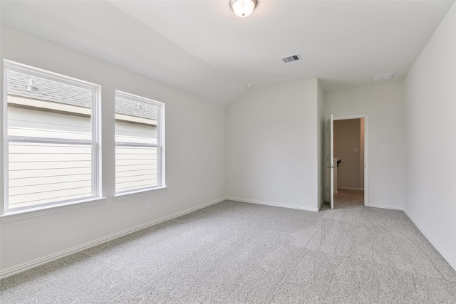 unfurnished room featuring visible vents, lofted ceiling, baseboards, and carpet floors