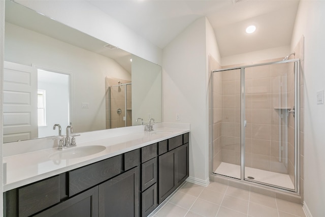 bathroom featuring tile patterned floors, a shower stall, double vanity, and a sink