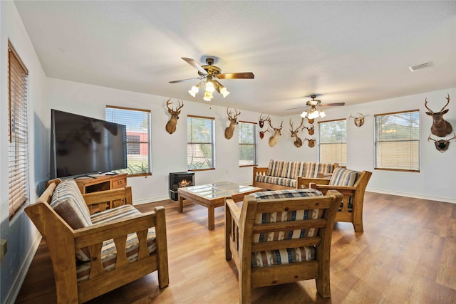 dining room with light hardwood / wood-style floors, a wood stove, and ceiling fan