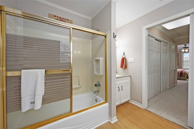 bathroom with ceiling fan, bath / shower combo with glass door, vanity, wood-type flooring, and ornamental molding