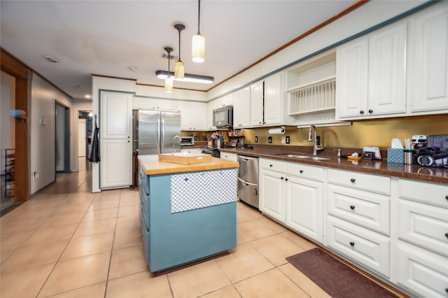 kitchen featuring a kitchen island, stainless steel appliances, wood counters, decorative light fixtures, and white cabinets