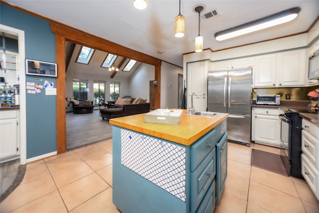 kitchen featuring wood counters, black / electric stove, stainless steel refrigerator, pendant lighting, and vaulted ceiling with skylight