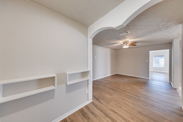 spare room featuring a textured ceiling, light wood-type flooring, and ceiling fan