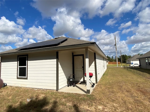 rear view of property featuring a yard, a patio area, and solar panels