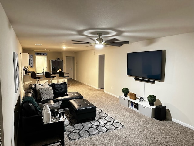 living room with ceiling fan, baseboards, and light carpet