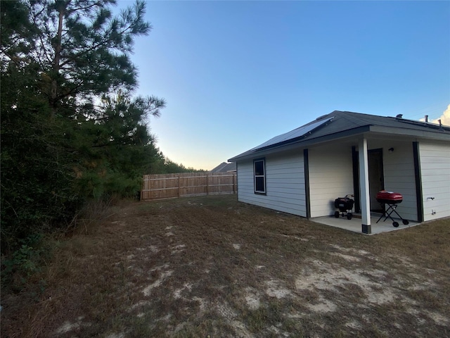 view of side of home featuring solar panels, a patio area, and fence