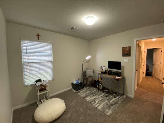 carpeted office space with visible vents, baseboards, and a textured ceiling