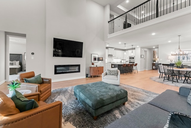 living room with light hardwood / wood-style flooring, a high ceiling, and a chandelier