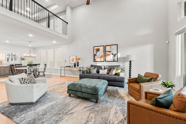 living room with hardwood / wood-style flooring, a towering ceiling, and a chandelier