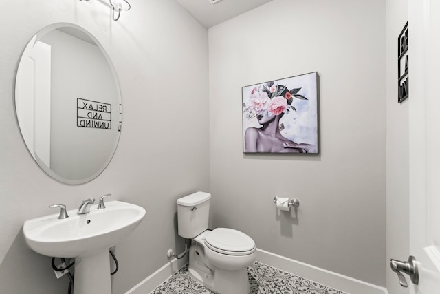 bathroom with sink, toilet, and tile patterned flooring