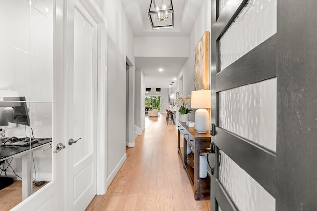 hallway with light hardwood / wood-style floors and a chandelier