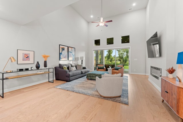 living room featuring light hardwood / wood-style floors, high vaulted ceiling, and ceiling fan