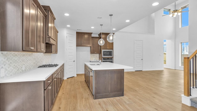 kitchen with pendant lighting, sink, ceiling fan, appliances with stainless steel finishes, and a kitchen island with sink