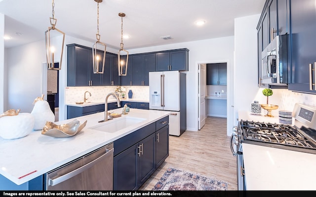 kitchen featuring backsplash, appliances with stainless steel finishes, light hardwood / wood-style flooring, pendant lighting, and sink