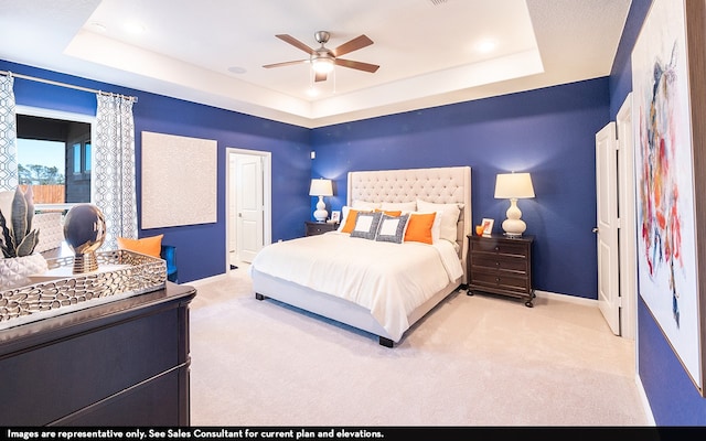 bedroom featuring light carpet, ceiling fan, and a raised ceiling