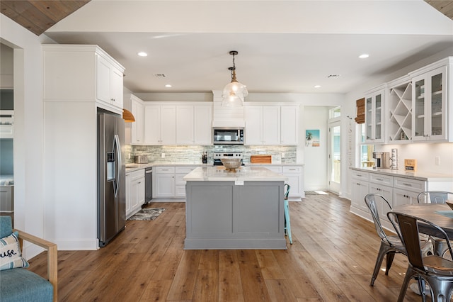 kitchen featuring appliances with stainless steel finishes, white cabinetry, light hardwood / wood-style floors, and pendant lighting