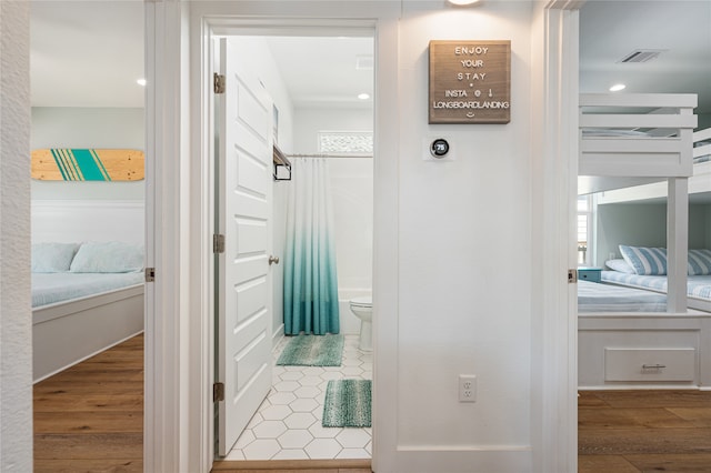 bathroom with hardwood / wood-style floors, a shower with curtain, and toilet