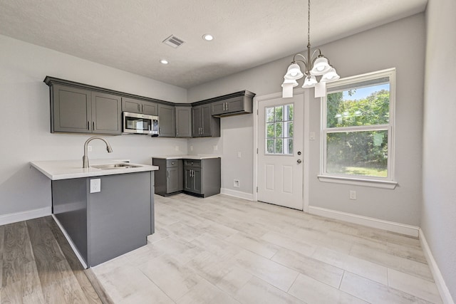 kitchen with gray cabinets, sink, light hardwood / wood-style flooring, and a textured ceiling